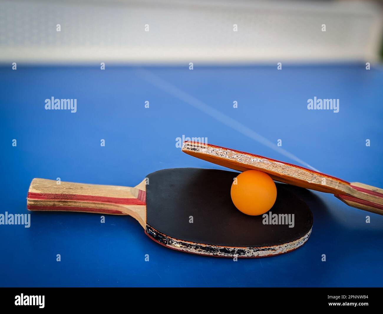 The professional ping pong rackets on a vibrant blue ping pong table, ready for game play Stock