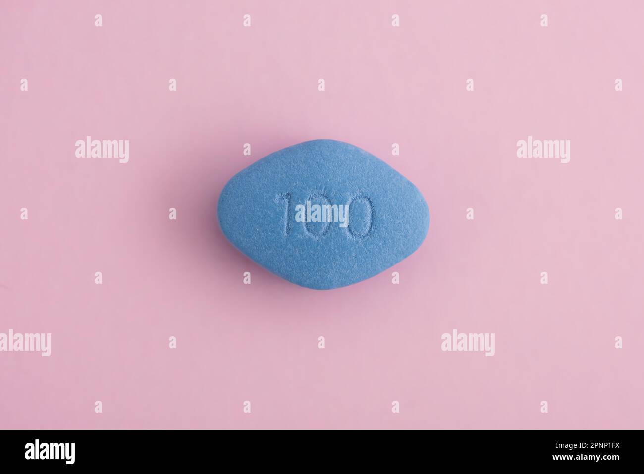 Blue pill on pink background. Medicine concept of medication for potency, erection, treatment of erectile dysfunction. Top view. Macro shot Stock Photo