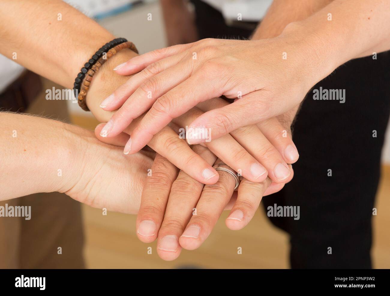 Four hands on top of each other as a sign of cohesion Stock Photo