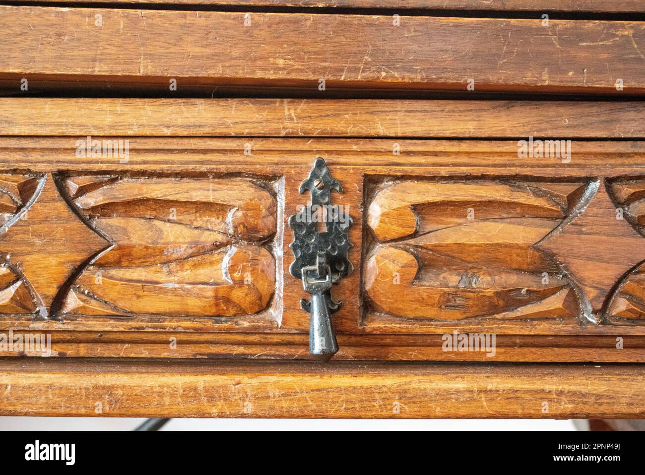iron Spanish style drawer handle on hand carved wooden drawer front