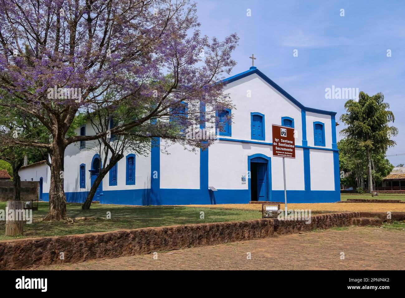 Historic church Santana do Santissimo with flowering tree and palms, Chapada dos Guimarães, Mato Grosso, Brazil Stock Photo