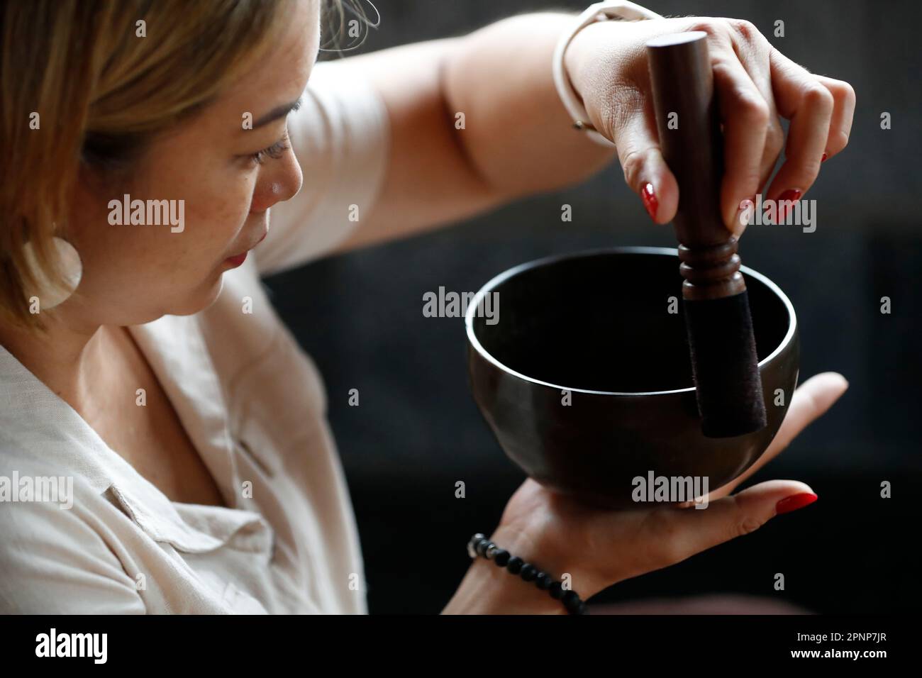 Tibetan singing bowl, buddhist instrument used in sound therapy, meditation and yoga.  Bowl in the hands of prayer.  Uong Bi. Vietnam. Stock Photo