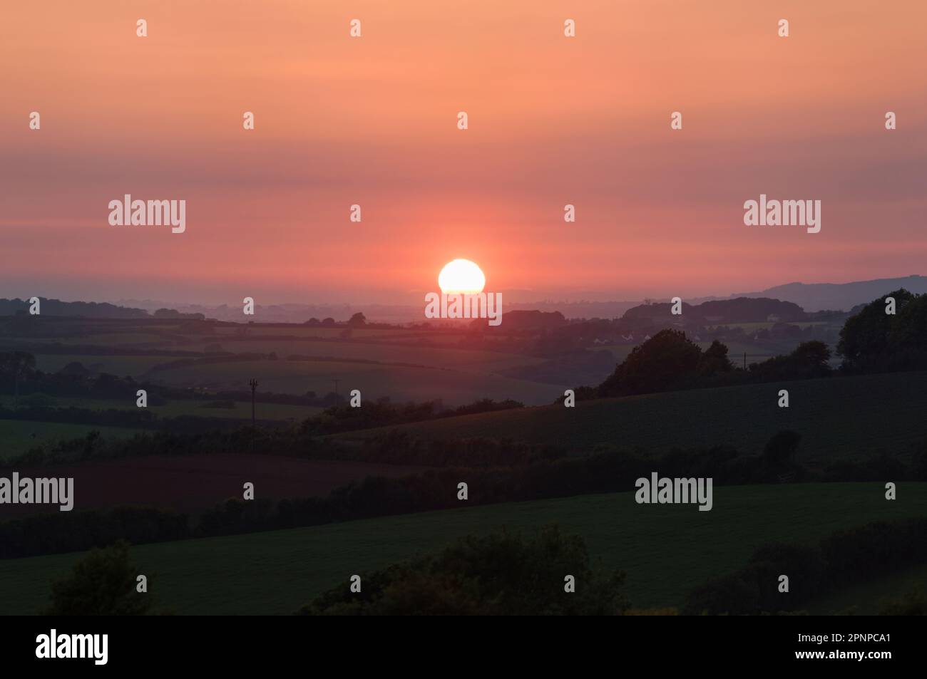 Sunsetting over the countryside of the Lizard Peninsula in Cornwall. The warm red sun setting over the English countryside on a summer day Stock Photo