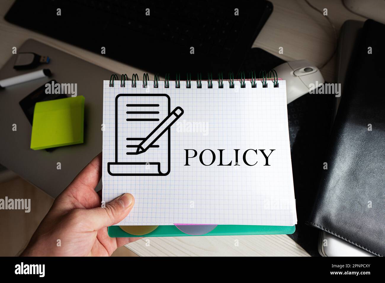 Policy word on notebook holding man against desktop Stock Photo - Alamy