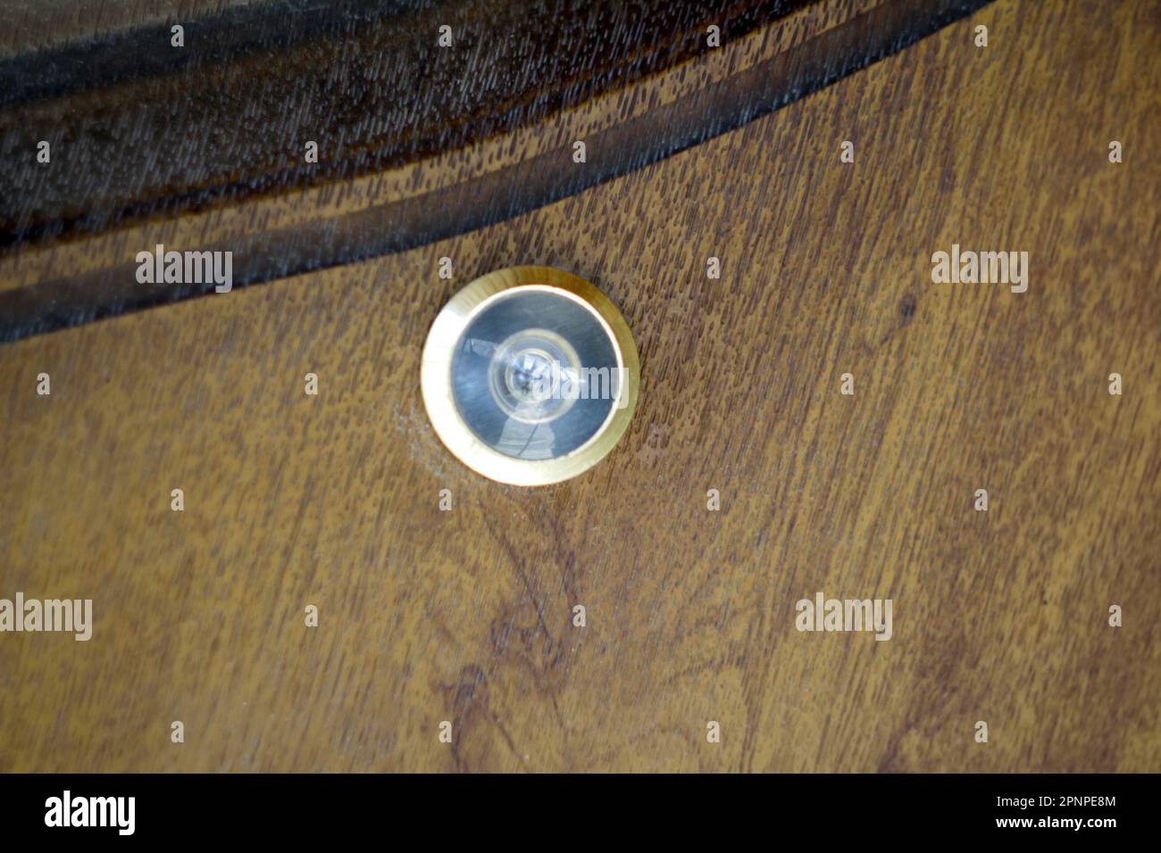 Close up eye hole on wood. close up, door lens peephole on white wooden texture. Door eye, at
