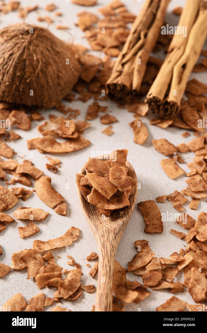 Coconut chips with cinnamon in wooden spoon, home drying. Vegan and
