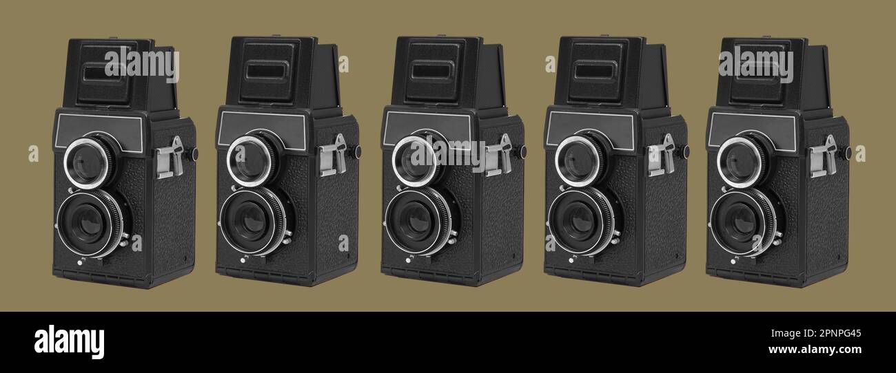 some black retro medium format film cameras on an olive green background in a panoramic format