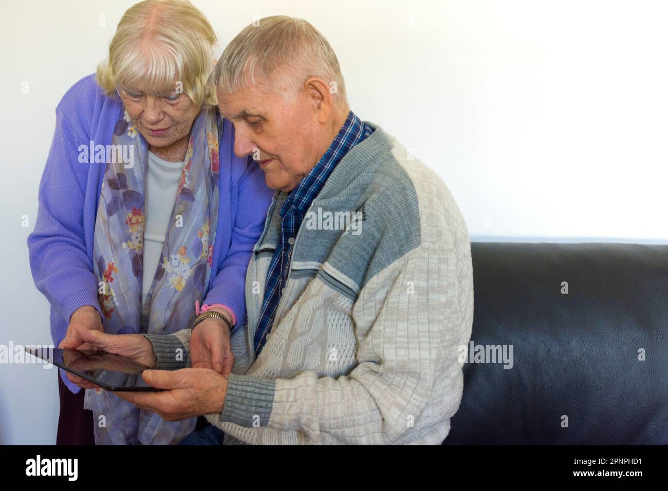 Senior elderly couple using a tablet computer with wifi broadband connection. Stock Photo