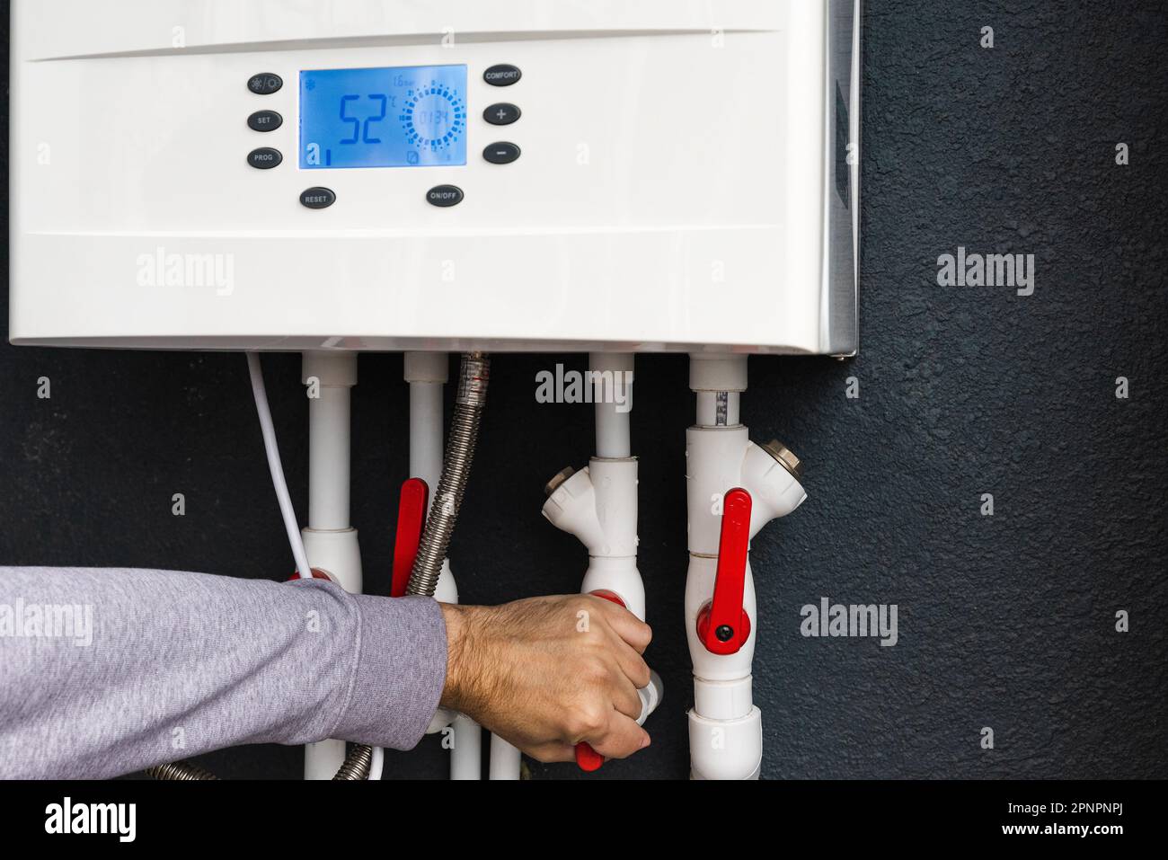 Worker hand remote or installing double-circuit gas boiler for winter home heating and water heating. Energy saving and heat conservation concept Stock Photo