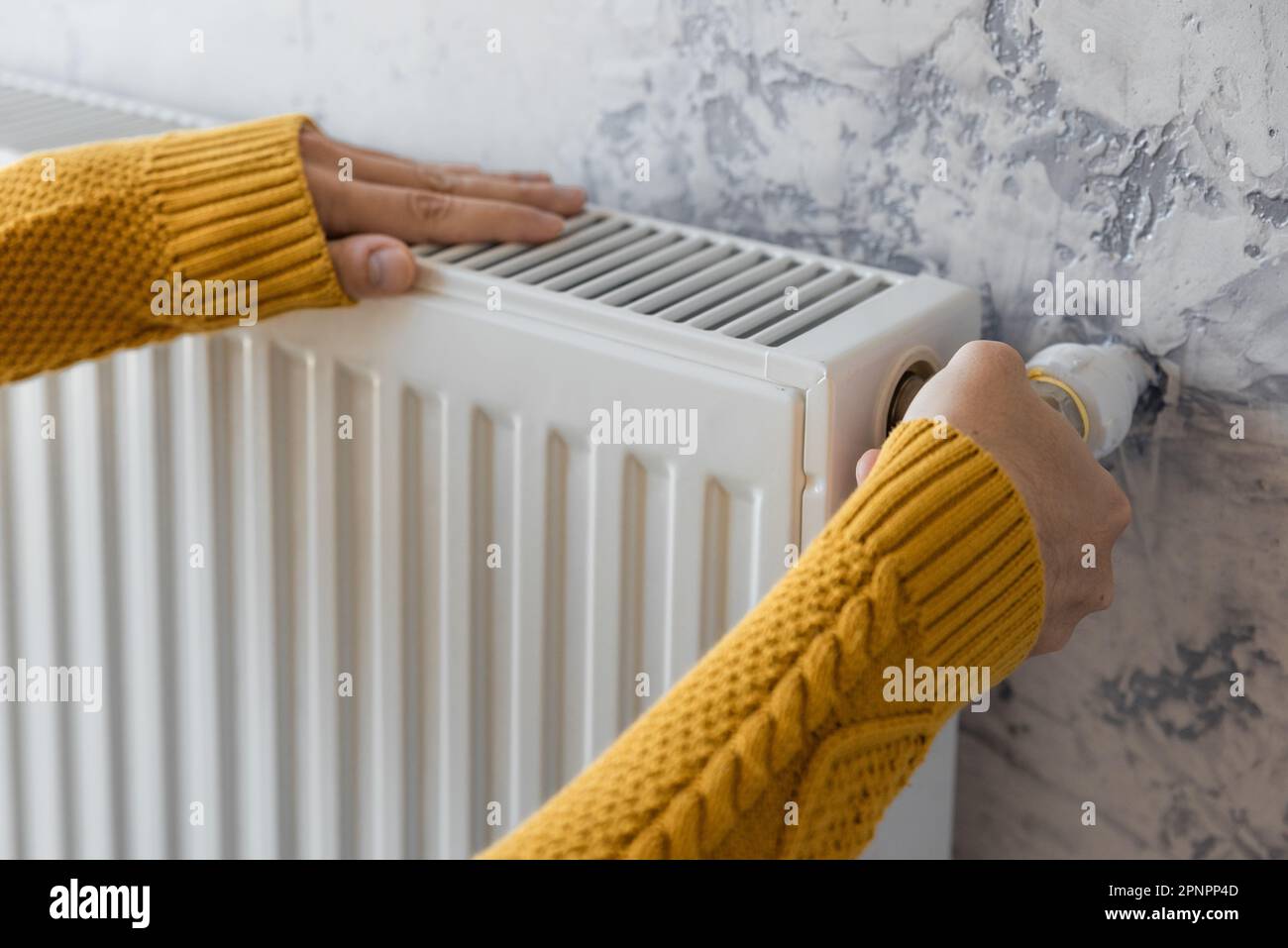 Man adjusting heating radiator or heater to install comfort temperature for energy efficiency and economy in winter. Concept of heating season Stock Photo