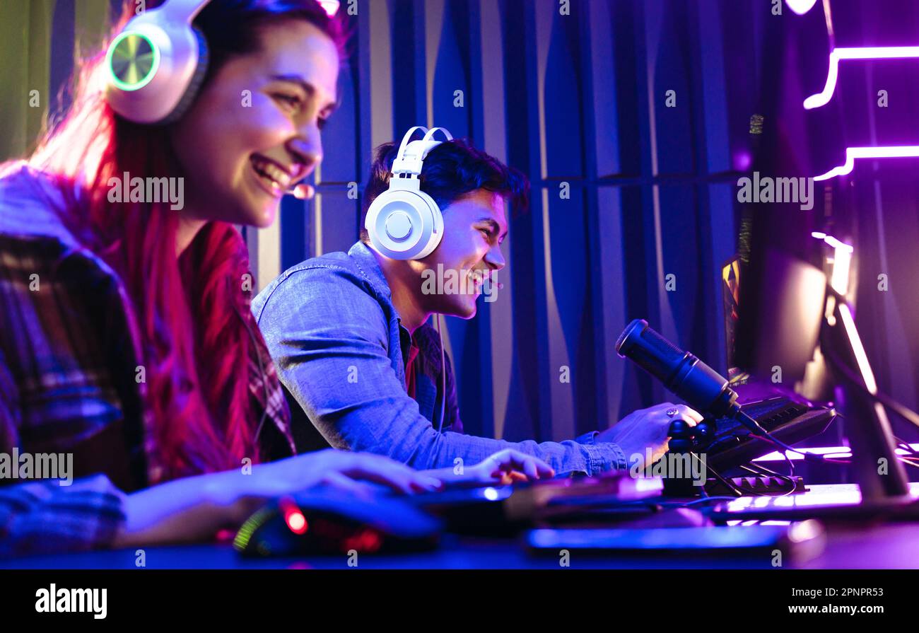 Two young gamers enjoying themselves as they engage in a fun online video game contest. Happy man and woman live streaming their play against each oth Stock Photo