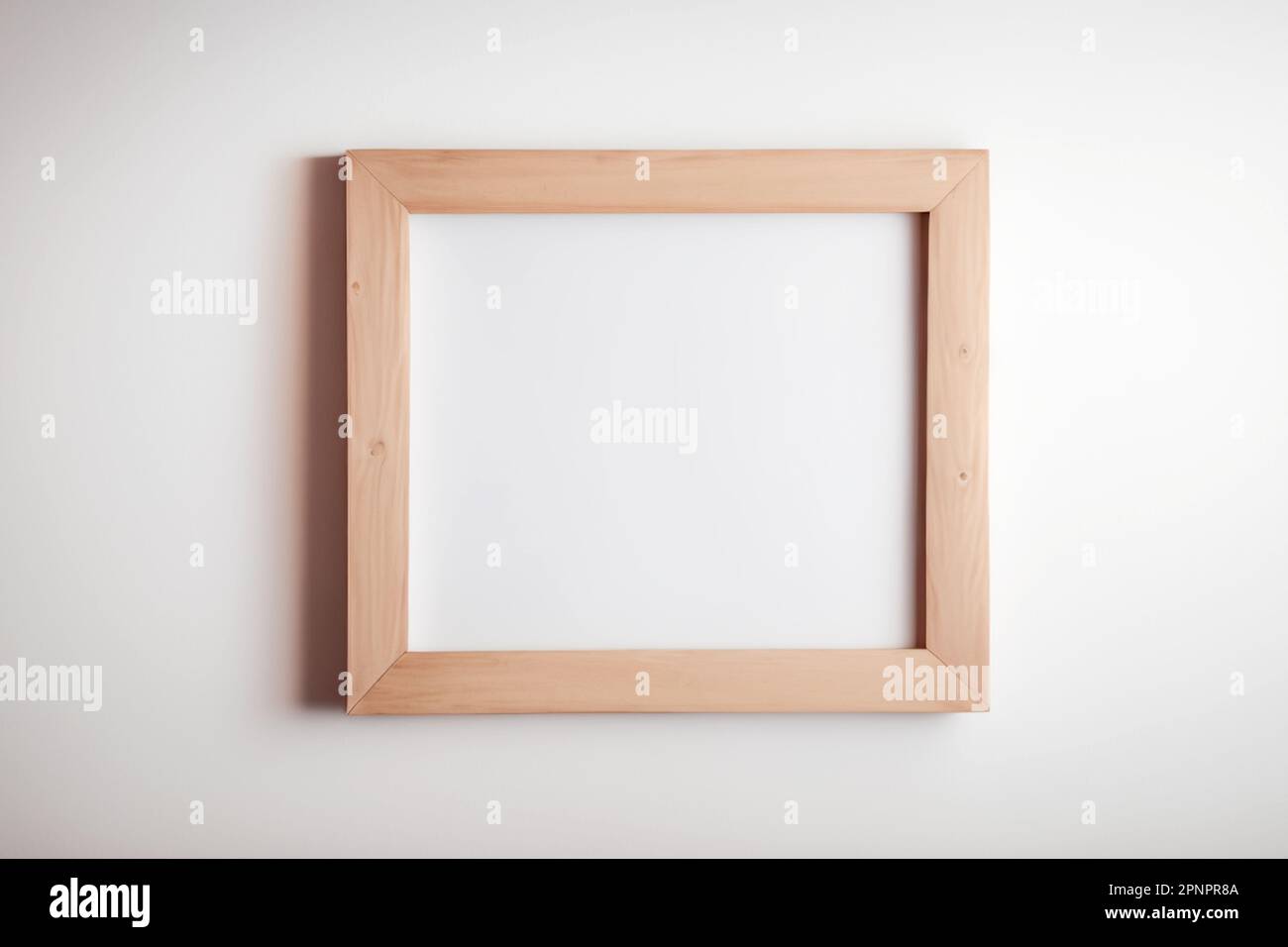 Light wood picture frame with square shape hanging on a white wall mockup for images and posters