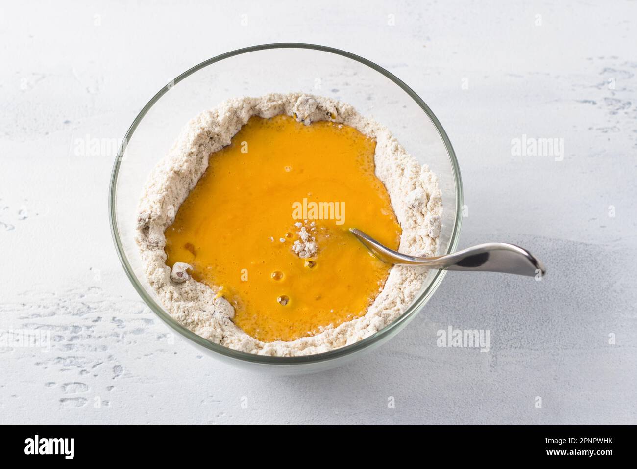 Glass bowl with oat flour and pumpkin puree, cooking pumpkin pancakes with oatmeal or cooking other dishes on a light gray background. Preparation hea Stock Photo