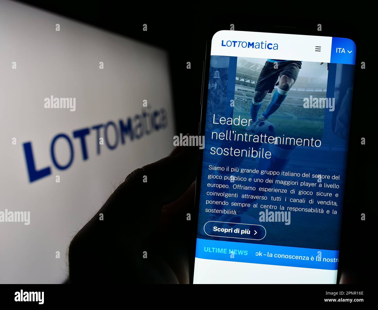 Person holding smartphone with website of Italian gambling company Lottomatica S.p.A. on screen with logo. Focus on center of phone display. Stock Photo