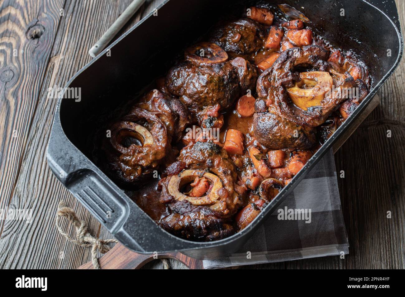 Braised beef shanks or ossubuco in roasting pot on wooden table. Stock Photo