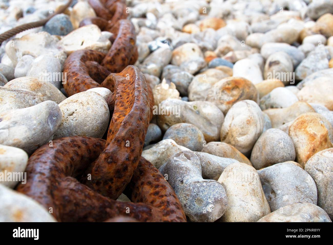 Chain, thick and rusty on the shingle beach in Yport Stock Photo
