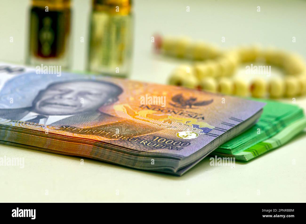 Close up of money, Indonesian rupiah banknote and perfume and prayer beads, in shallow focus Stock Photo