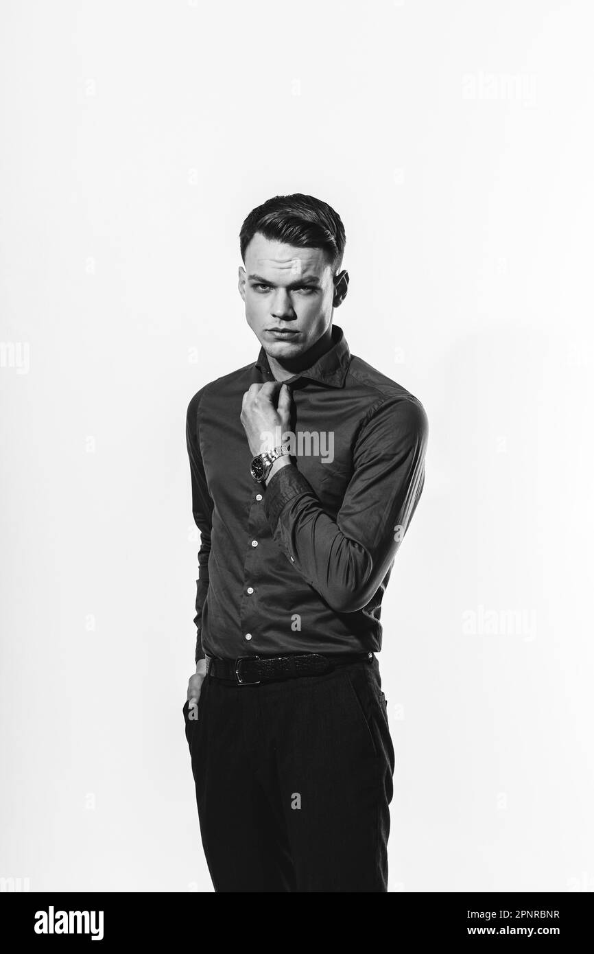 A stylish black and white portrait of a man in a shirt posing on a white cyclorama. Stock Photo