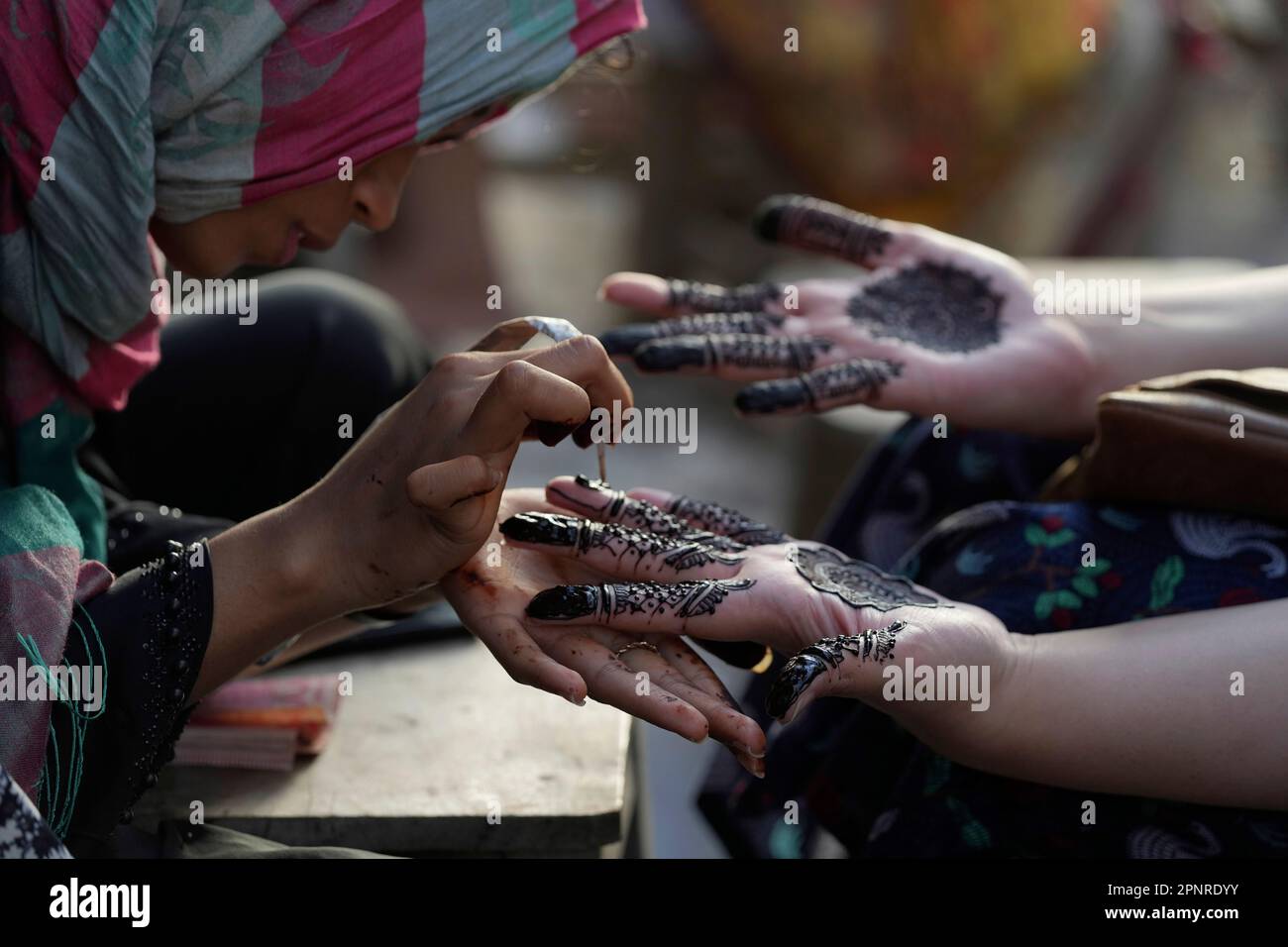 A beautician paints hands of customers with traditional henna in