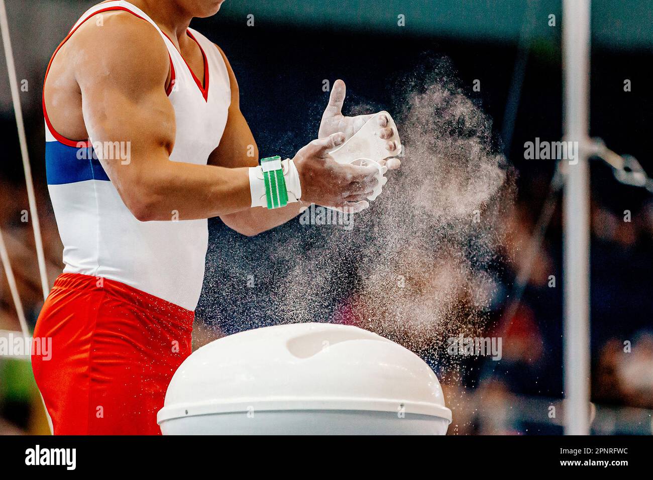 close-up hands male gymnast in gymnastics grips apply gym chalk from magnesia stands Stock Photo