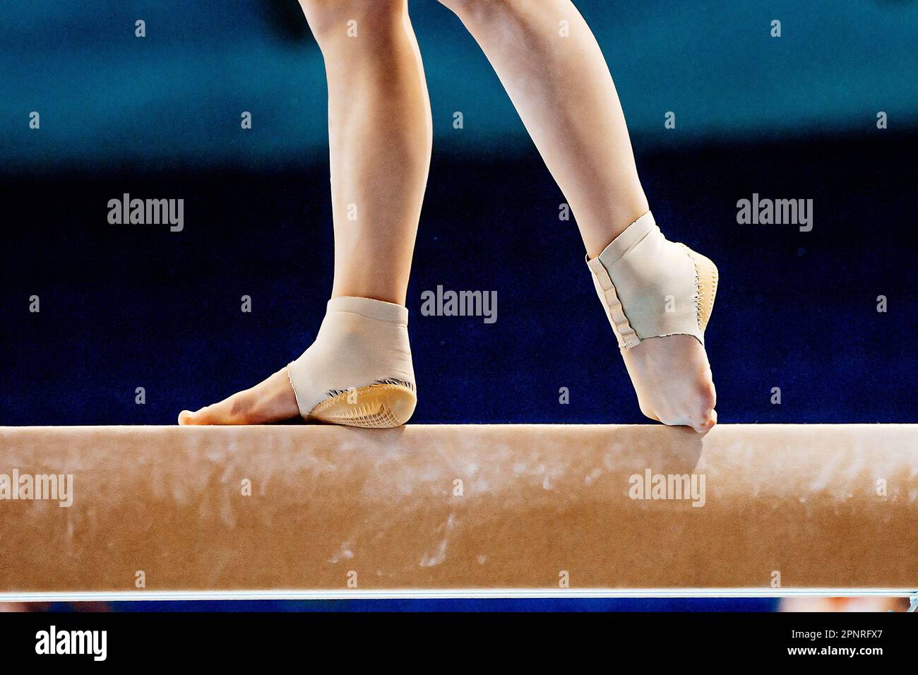 closeup legs female gymnast on balance beam in gymnastics, fitted neoprene ankle support with