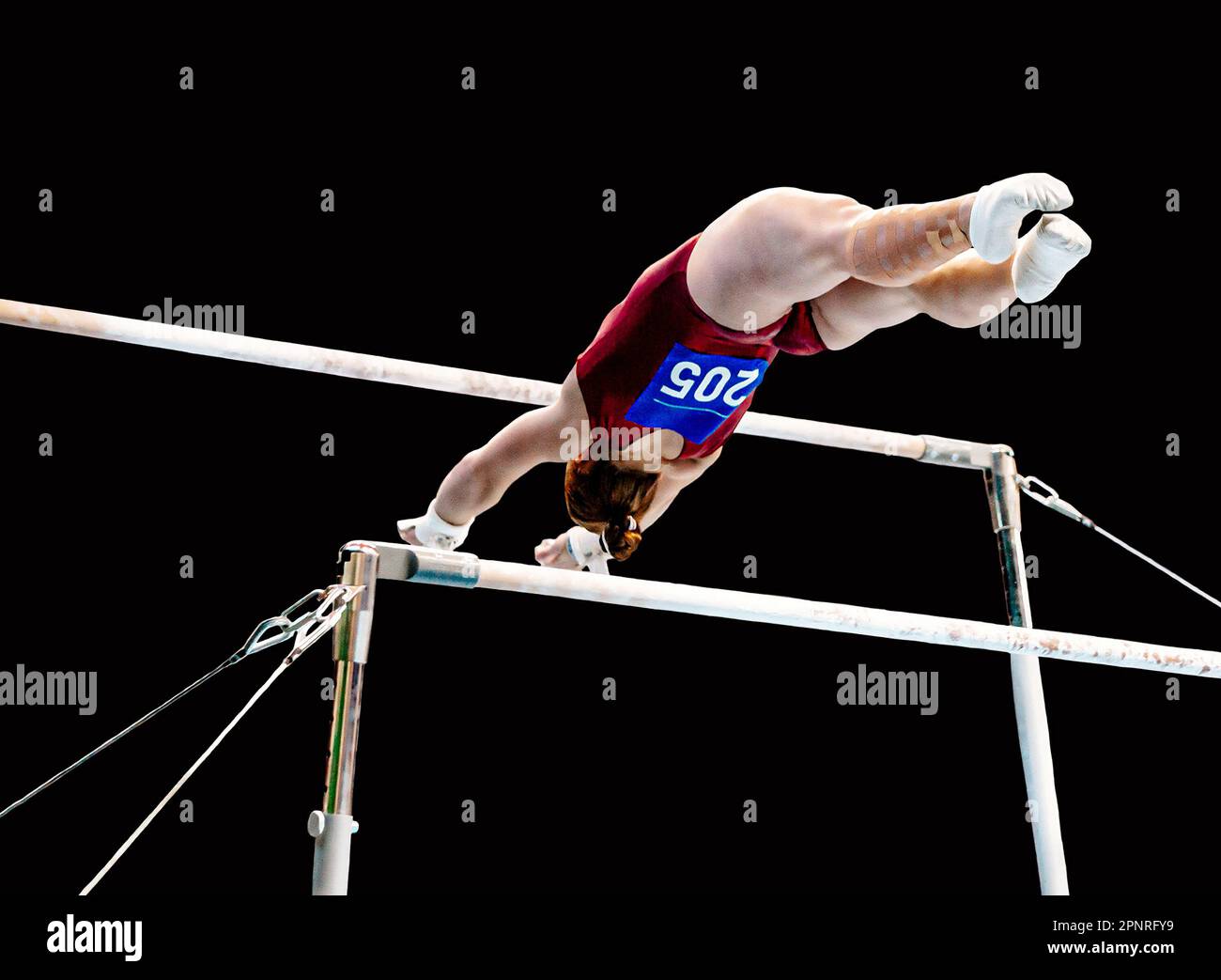 female gymnast exercise on uneven bars in gymnastics, black background, sports summer games Stock Photo