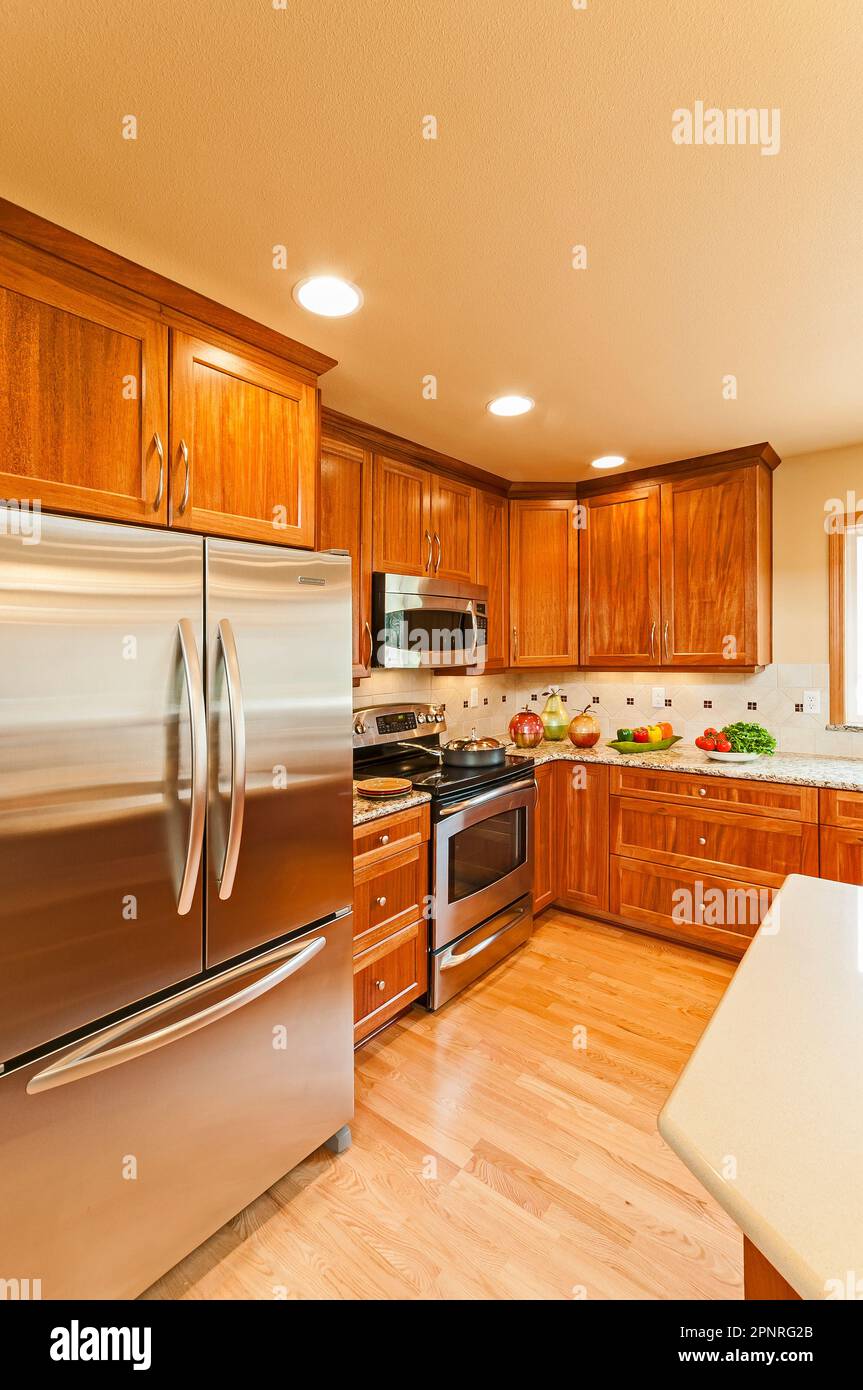 Wood cabinets, countertops, appliances, and hardwood floors in this contemporary house remodel. Stock Photo