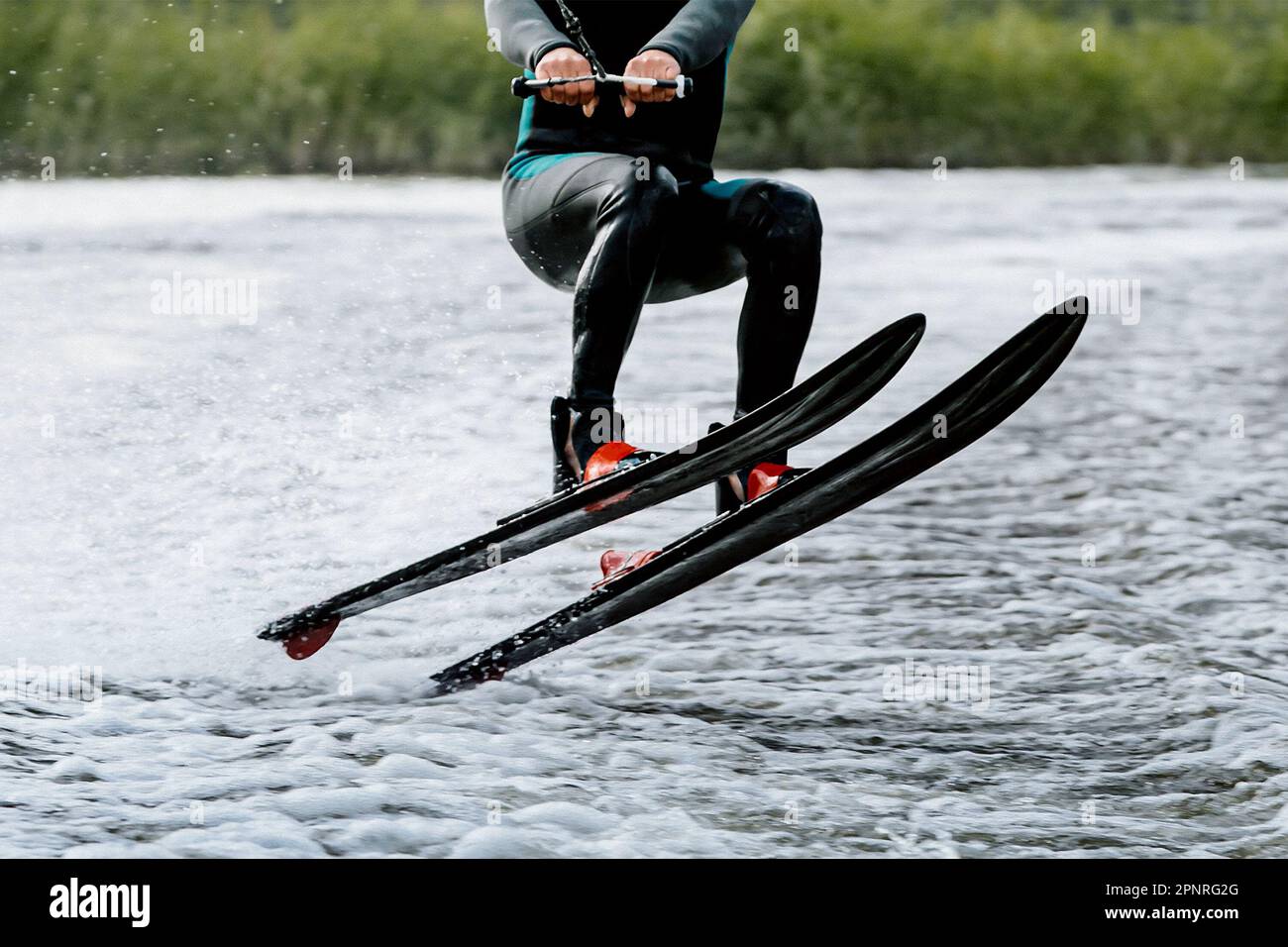 athlete jump waterskiing behind motor boat on lake, extreme summer water sports Stock Photo