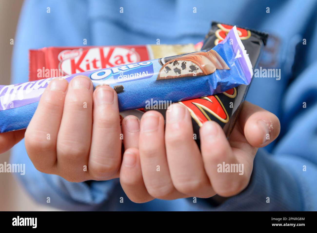Arahal. Seville. Spain. March 18, 2023. Hands of a child holding chocolates from different brands. Excessive consumption of sugar can have negative co Stock Photo