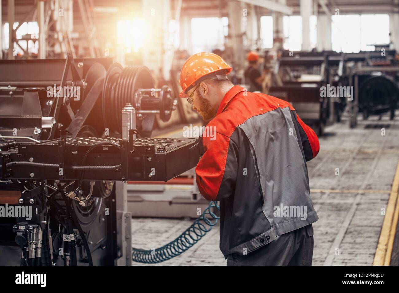Industrial worker assembles agricultural machine in workshop. Stock Photo