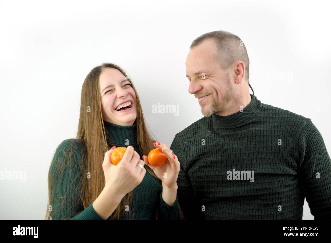 Happy laughing couple kissing talking and peeling tangerines. Pregnant