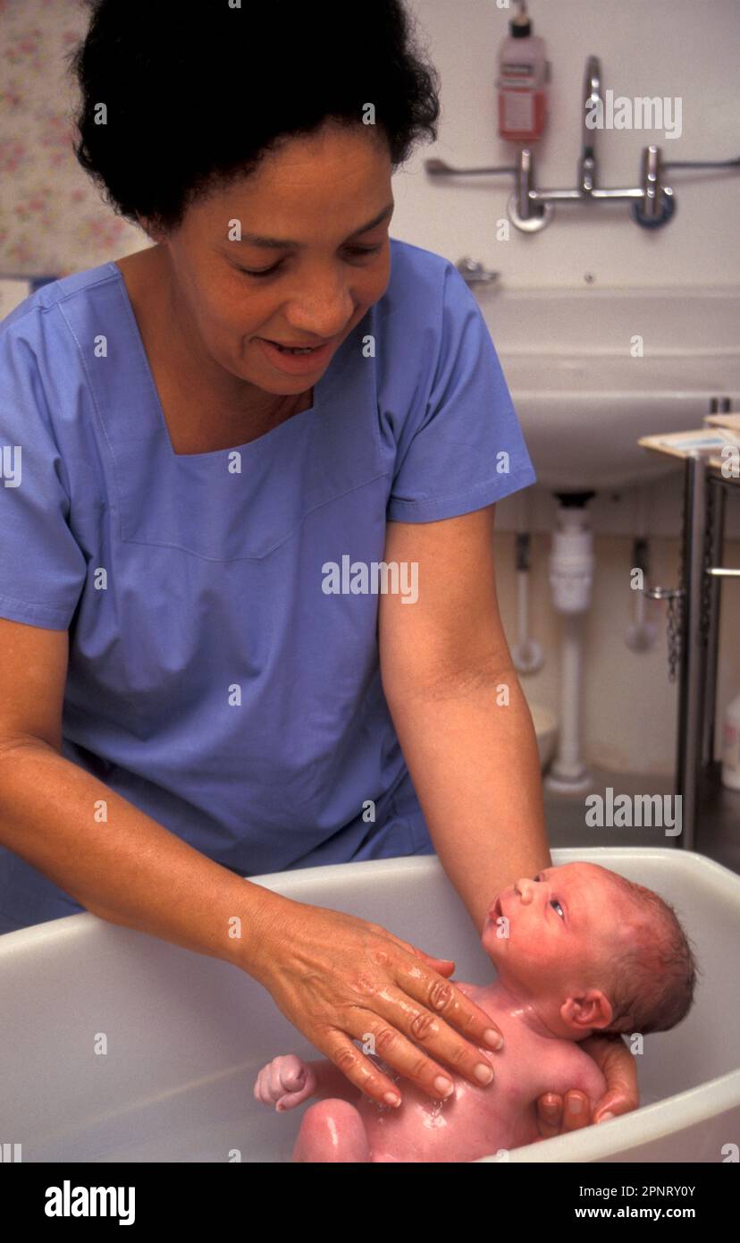 midwife of west indian origin bathing newborn baby Stock Photo