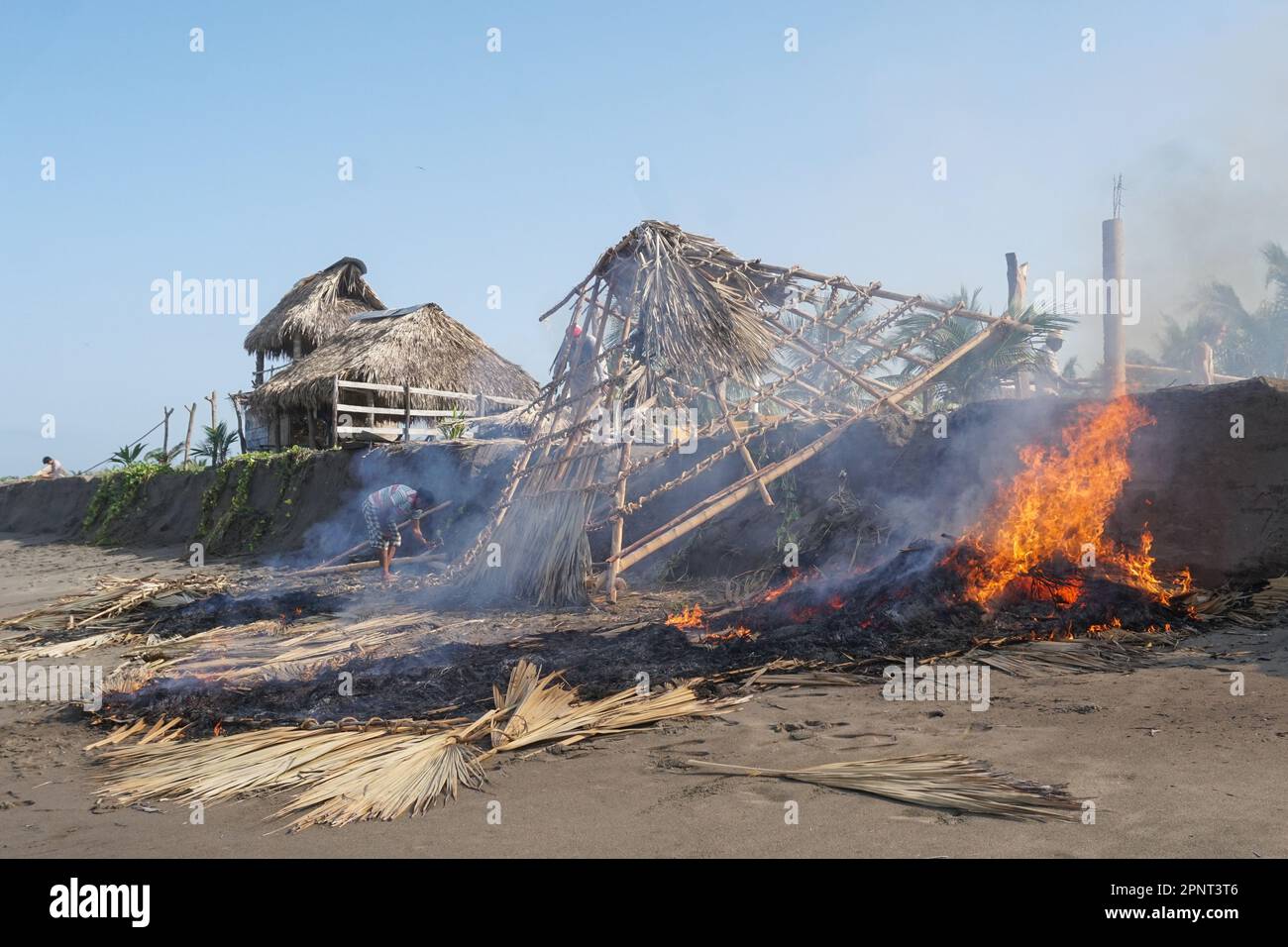 Rogelio Gutiérrez, left, and Gabriel Ruiz López deconstruct palm-thatched shelters on the beach in Boca del Cielo in Chiapas, Mexico on July 31, 2021. Rising tides inundate the beach more often now, so shelters are taken apart to reuse the material. (Marissa Revilla/Global Press Journal) Stock Photo