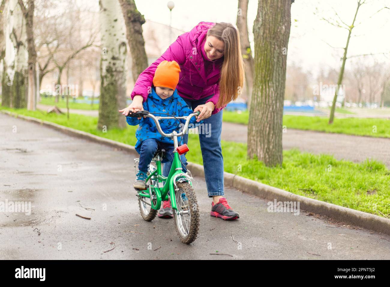 Young mom teaching son to ride bike first time in park Stock Photo Alamy