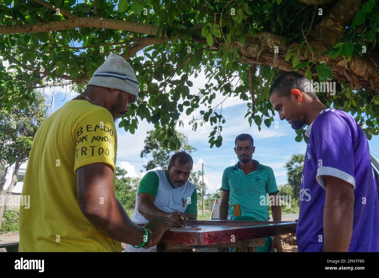 From left, Christhobar Ajith, Mohammathu Sathaku Yasin, Ravuthar Mohammathu Pasith and Mohammathu Imthiyas Infan play carom as they wait for three-wheeler customers in a parking lot in Mannar, Sri Lanka on April 14, 2022. (Vetrichelvi Chandrakala/Global Press Journal) Stock Photo