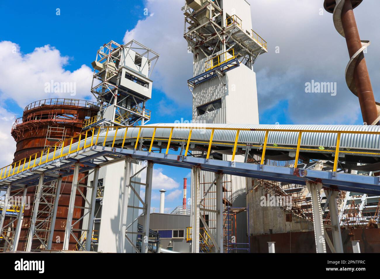 Metal iron structures, industrial production with a conveyor, pipes, railings and pipelines at the production of an oil refining petrochemical plant. Stock Photo