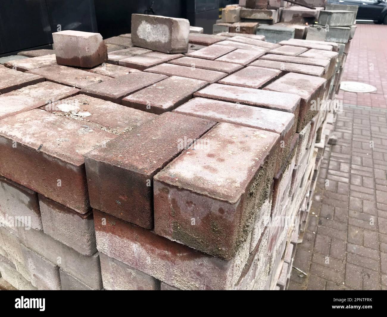 Paving stone red cement tile for laying road construction, pavement on wooden pallets at a construction site. Stock Photo