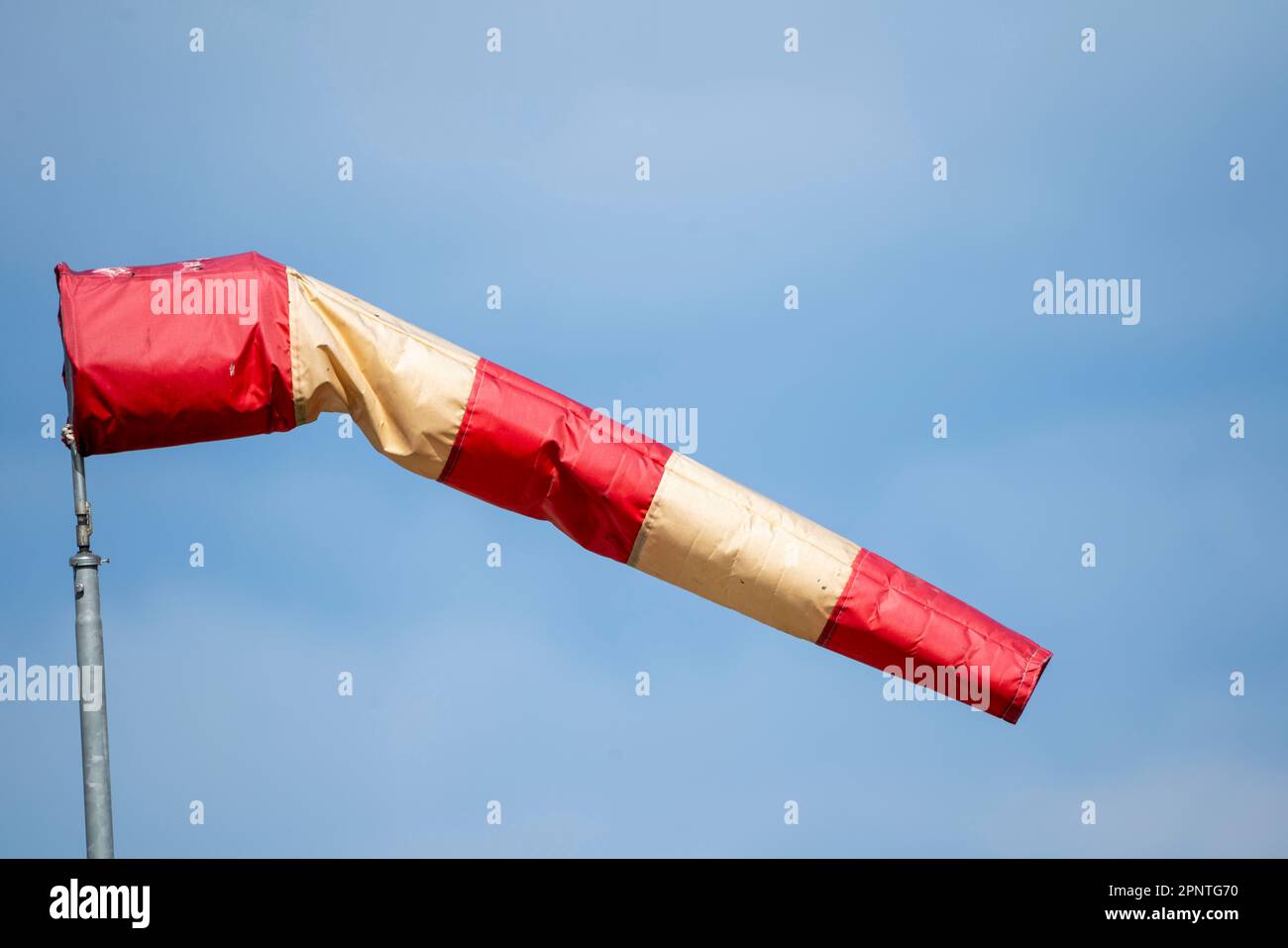 Red and white windsock at an airport, showing wind direction and strength, Stock Photo