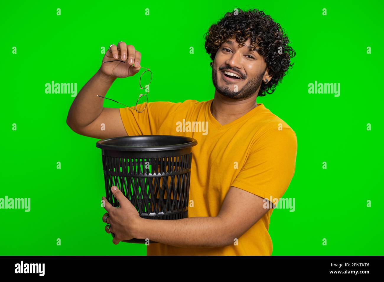 Indian bearded man taking off throwing out glasses into bin after medical vision laser treatment therapy surgery looking smiling at camera. Handsome hindu guy isolated alone on chroma key background Stock Photo