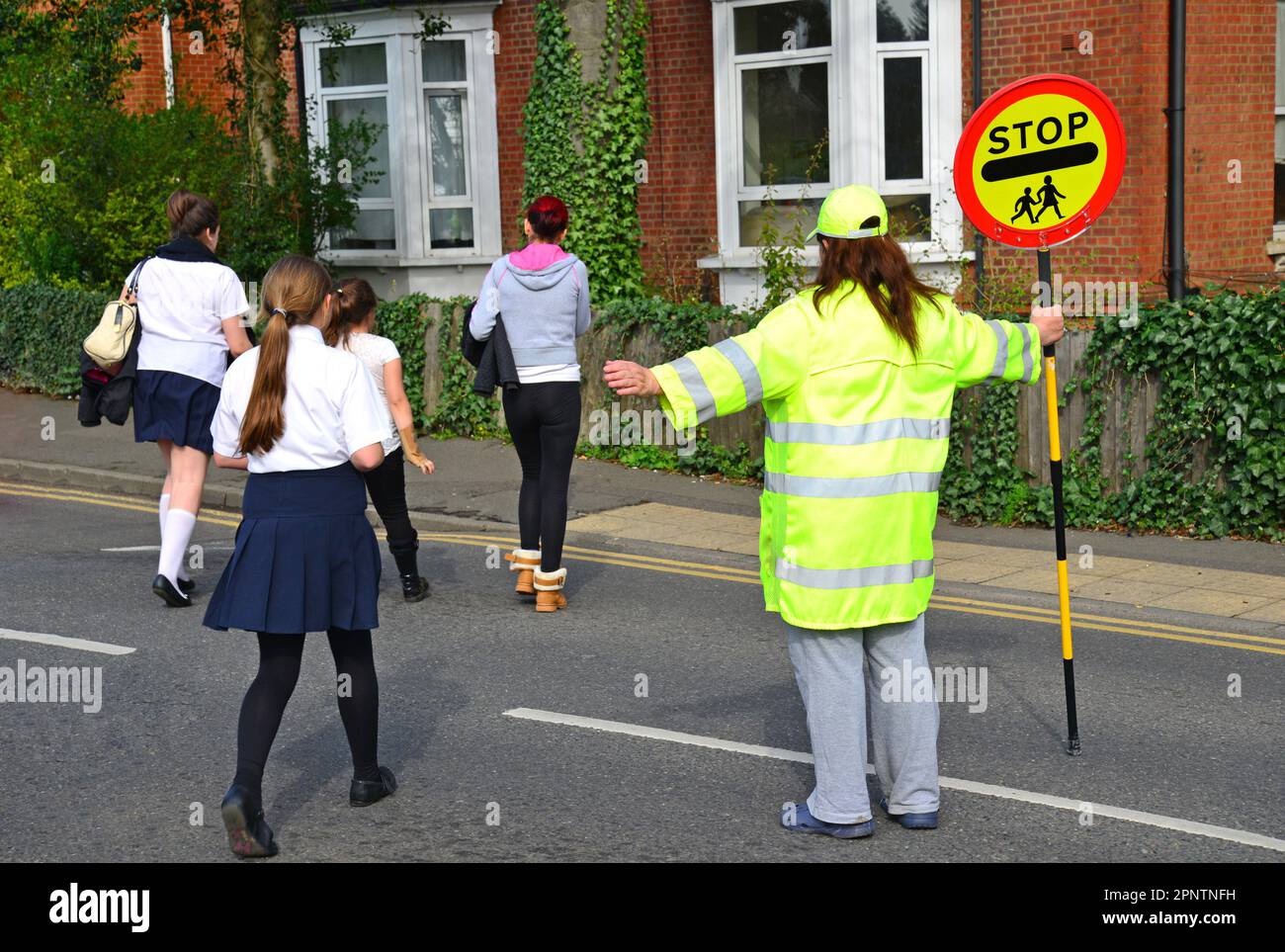 School pedestrian crossing monitor (lollipop woman), St.Jude's Road, Englefield Green, Surrey, England, United Kingdom Stock Photo