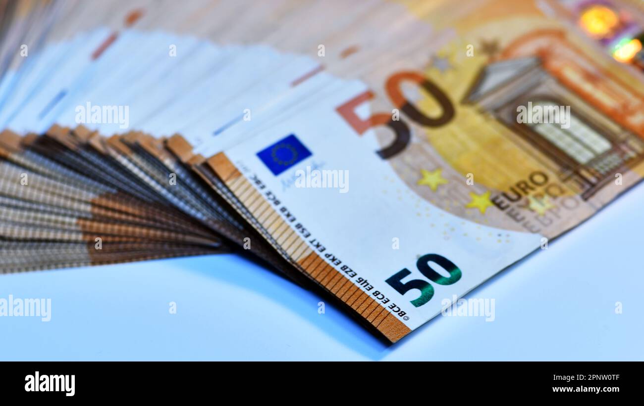 Concept of many euros: a pile of rolled 50-euro bills lying on a white background to the tune of thousands of euros in 50-euro bills Stock Photo