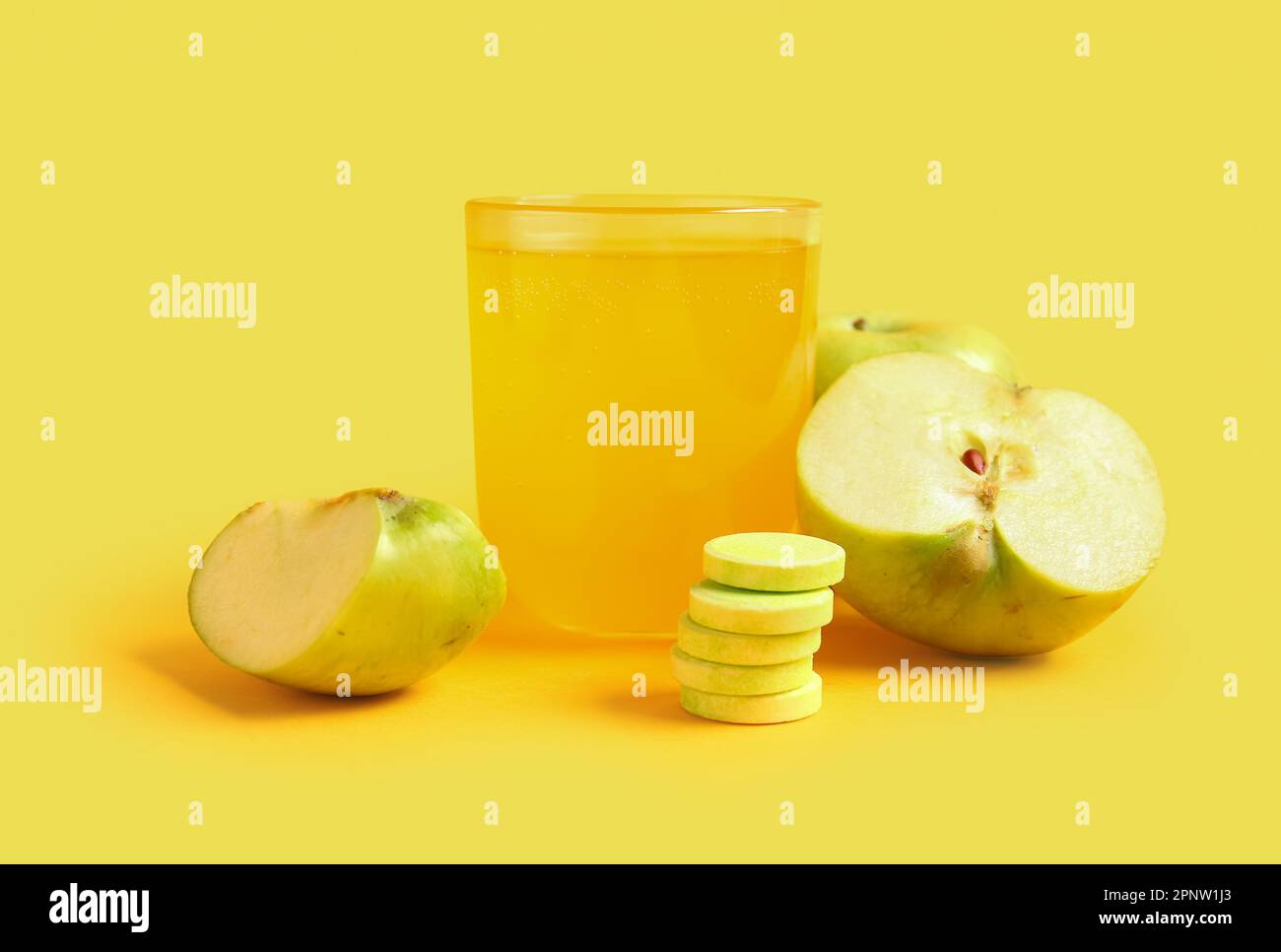 Glass of vitamin C effervescent tablet dissolved in water and apples on