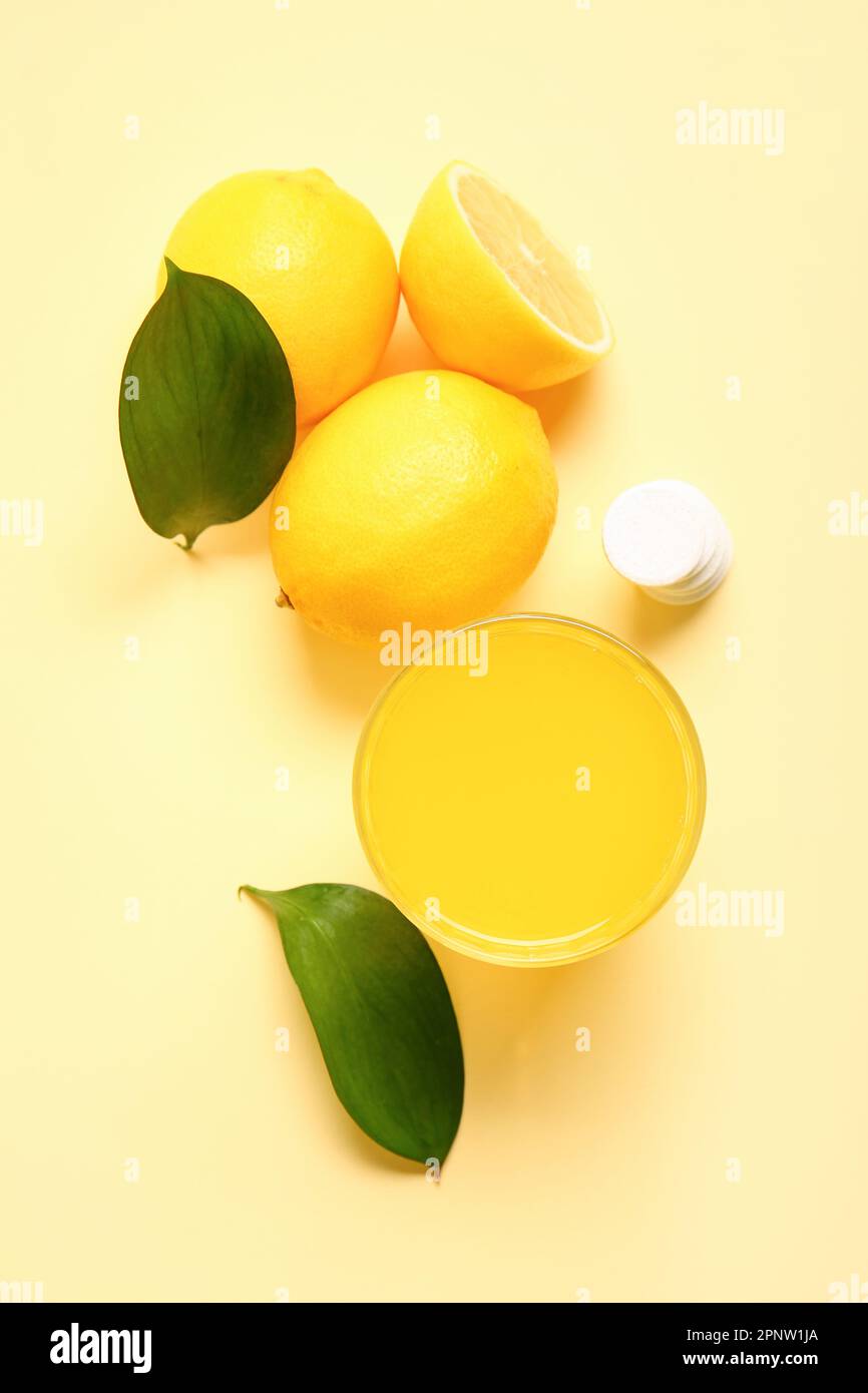 Glass of vitamin C effervescent tablet dissolved in water and lemons on