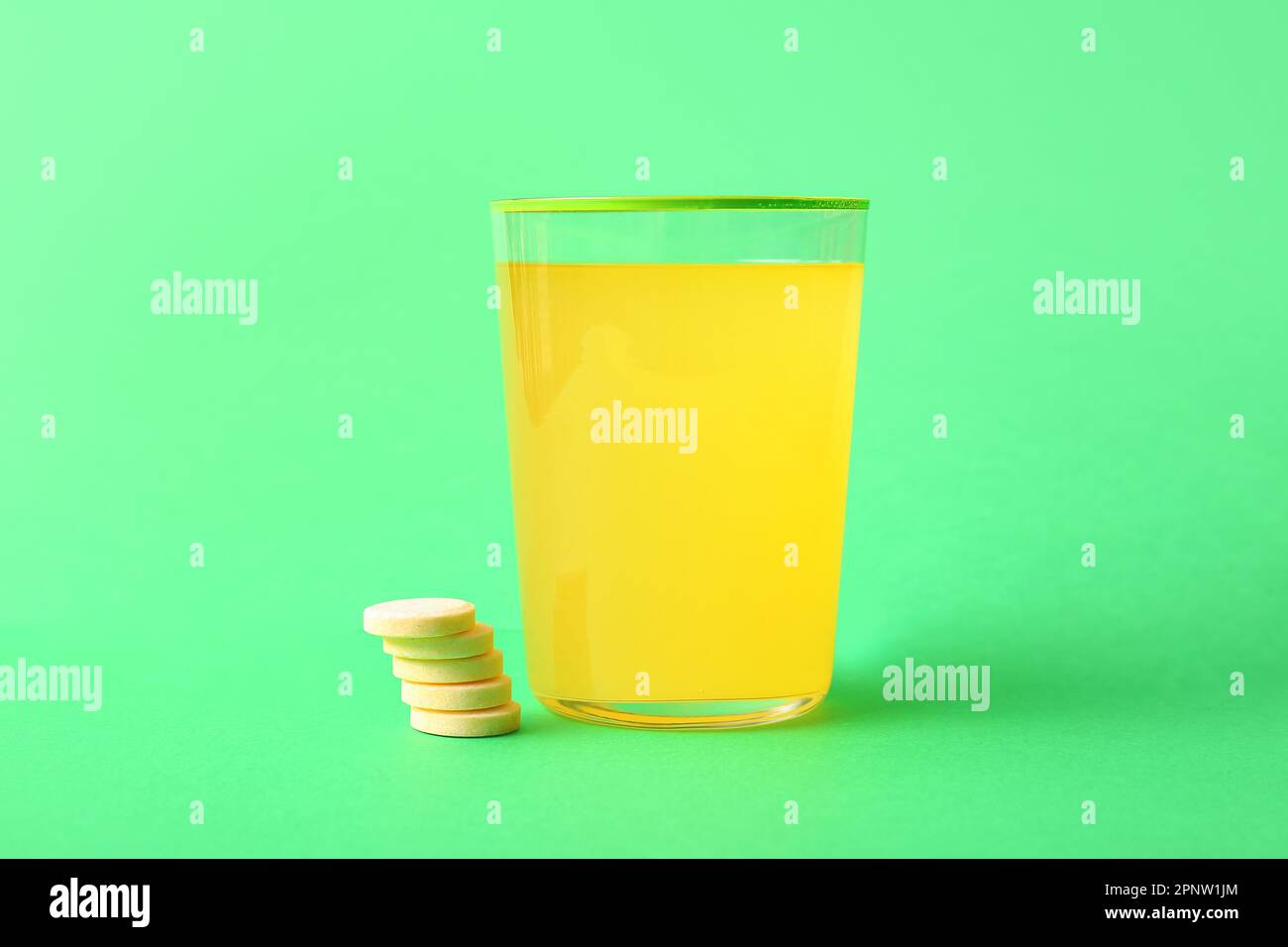Glass of effervescent tablet dissolved in water on green background