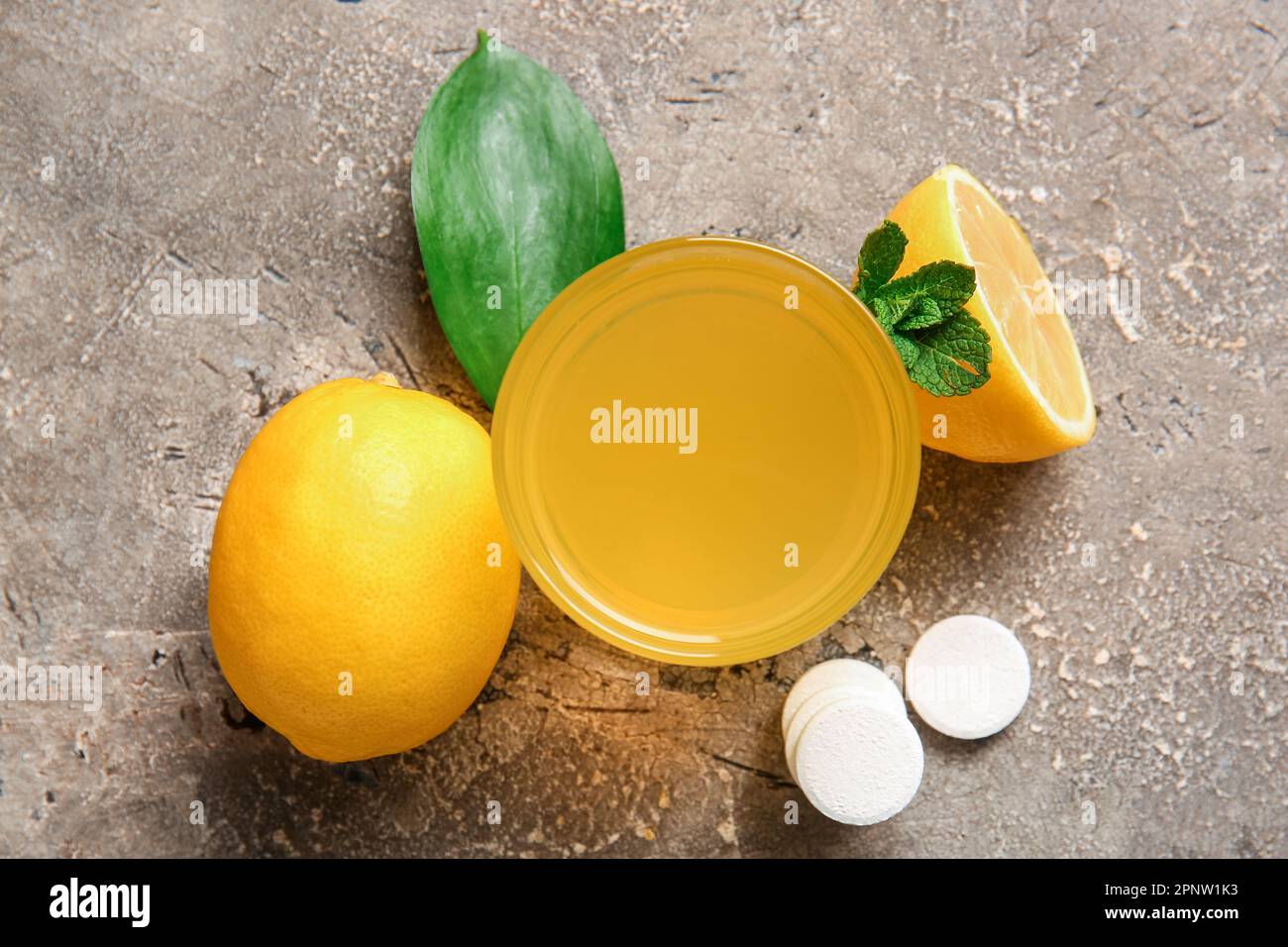 Glass of vitamin C effervescent tablet dissolved in water and lemons on