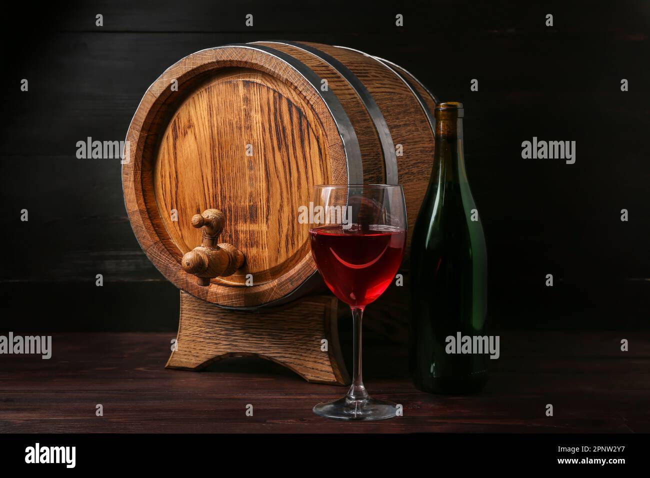 Oak barrel with bottle and glass of wine on dark wooden background ...