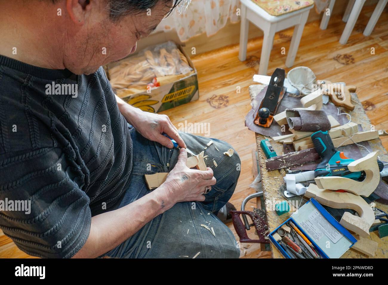 Purevbaatar Tserendash carves the head of a morin khuur, also known as a horsehead fiddle, in Murun, Khuvsgul province, Mongolia on January 24, 2022. Purevbaatar, who has been making instruments for 10 years, says the sound of the fiddle keeps evil at bay. (Dolgormaa Sandagdorj/Global Press Journal) Stock Photo