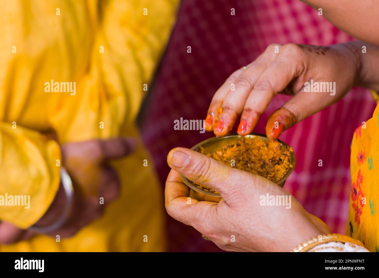 Bengali marriage rituals of Gaye holud where traditional women applies turmeric paste on bride