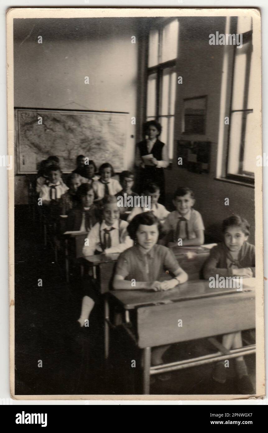 Vintage photo shows pupil sit at the school desk in classroom. Stock Photo