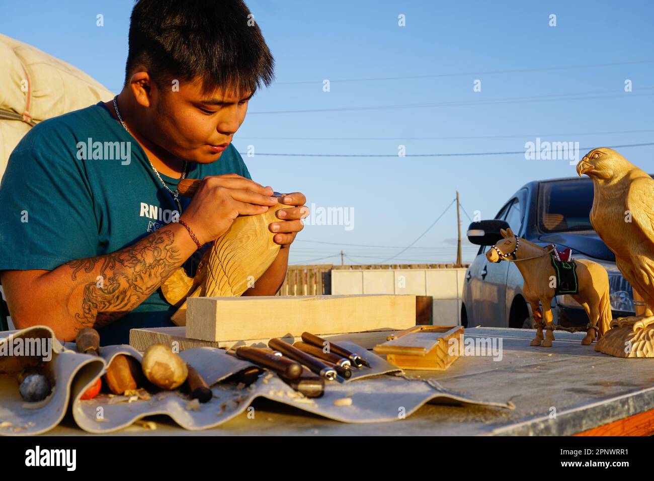 Altangerel Munkhjargal carves a wooden falcon in Dalanzadgad, Umnugovi province, Mongolia on August 23, 2022. Altangerel, who took a gap year during the coronavirus pandemic, started carving in his idle time. (Uranchimeg Tsoghuu/Global Press Journal) Stock Photo